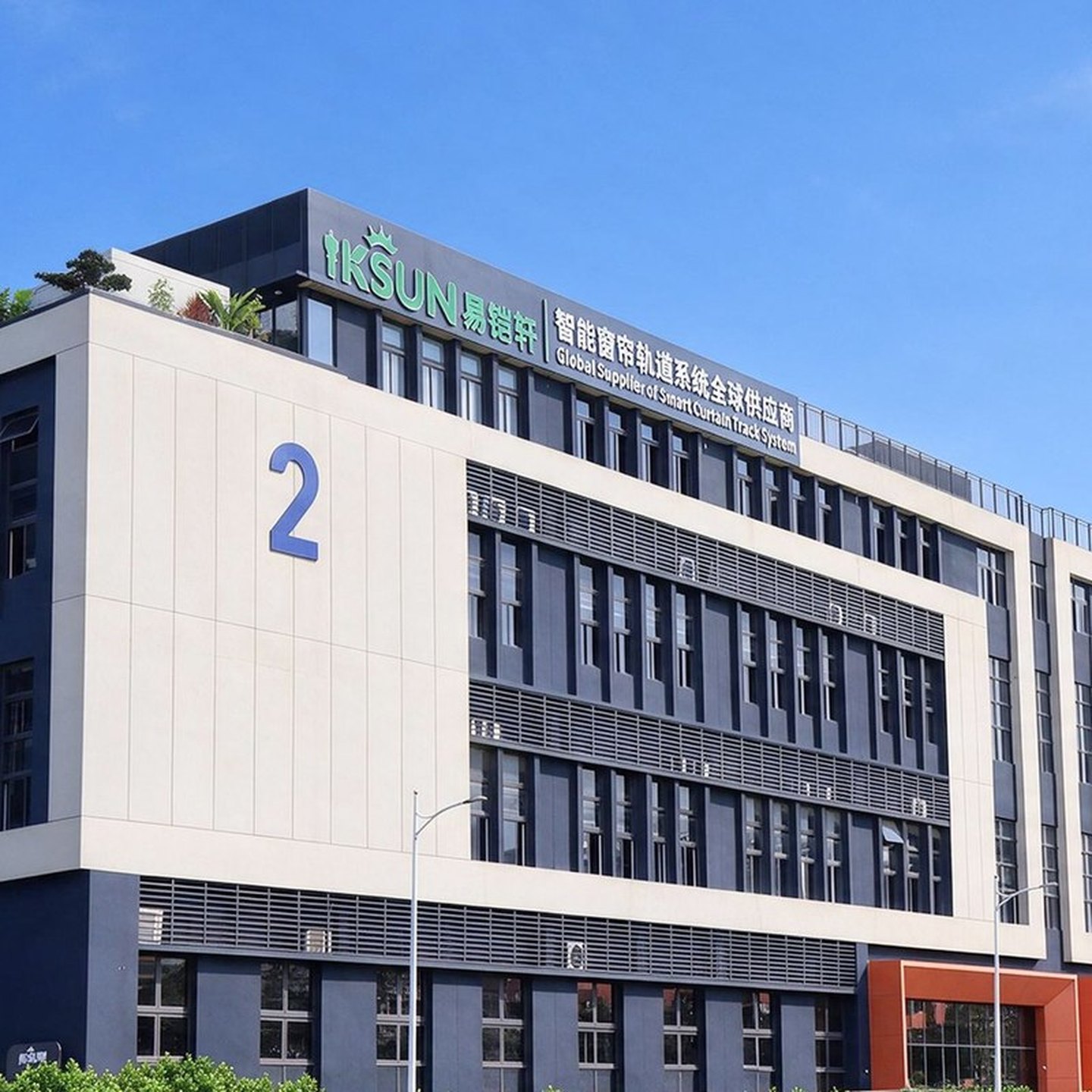 The IKSUN factory building in Foshan, with the company name and 'Global Supplier of Smart Curtain Track System' on the rooftop